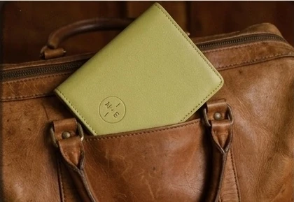 Le porte-passeport posé sur un sac de cuir fauve, monogramme visible
